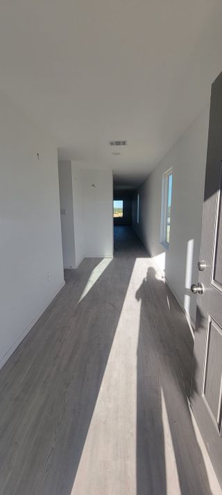 A bright, minimalist hallway with wood flooring and ample natural light through large windows.