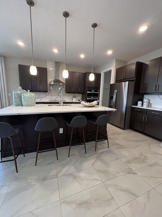 A sleek kitchen with dark cabinets, pendant lighting, and a spacious island with stylish seating.