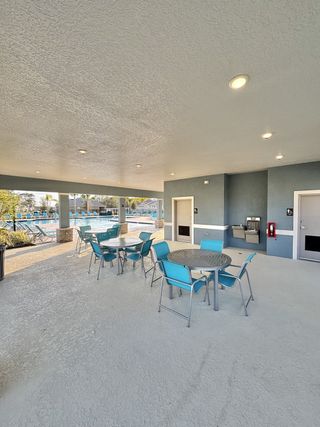 A covered outdoor seating area with vibrant blue chairs overlooking the community pool in Concorde by D.R. Horton (Sanford, FL).