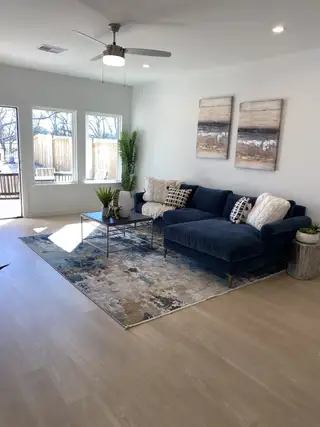 Model Home A cozy living room with a plush navy sectional, stylish decor, and ample natural light from large windows.