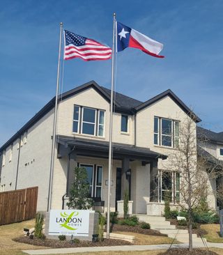 Elegant white brick home with twin flags, located in Duets 41s by Landon Homes in Frisco, TX.