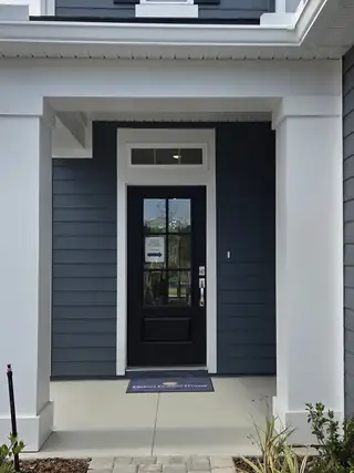 A welcoming navy blue front porch in Brook Forest by Dream Finders Homes, St. Augustine, FL.
