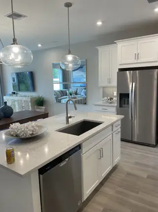 A modern kitchen with sleek white cabinets, stainless steel appliances, and stylish pendant lighting.