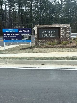 Street view Brick signage and lush greenery welcome you to Azalea Square Townhomes by Century Communities in Lawrenceville, GA.