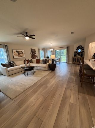 A spacious living area with light wood flooring, cozy sectional, and modern decor, opening to a serene outdoor view.