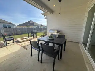Model Home A cozy patio with modern black furniture, a grill, and a fire pit, perfect for outdoor gatherings.