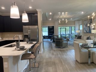 An open-concept living space with a sleek kitchen, cozy seating, and modern lighting in neutral tones.