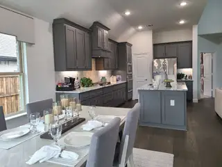A modern kitchen with gray cabinetry, an island, and a dining area set for guests, featuring elegant decor.