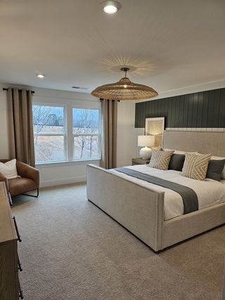 A serene primary bedroom featuring a dark accent wall, large windows, and soft neutral tones for a peaceful retreat.