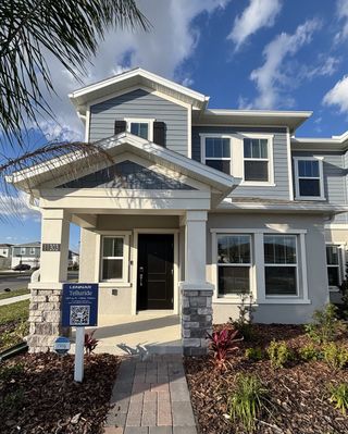 Street view A charming gray two-story home with white trim and a manicured yard in EverBe: Venture Townhomes by Lennar (Orlando, FL).