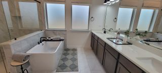 A chic bathroom with a freestanding tub, dual sinks, and elegant black fixtures, complemented by soft natural light.