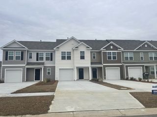 A charming row of modern townhomes with neutral siding in Pine Hills Townhomes at Cane Bay by D.R. Horton (Summerville, SC).