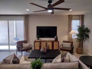 A cozy living room featuring a sleek ceiling fan, sliding doors, and stylish furnishings, creating a welcoming atmosphere.