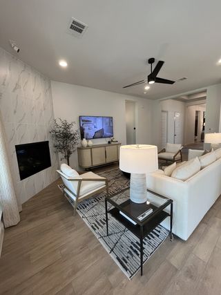 A modern living room with a sleek fireplace, wood flooring, cozy seating, and contemporary decor.
