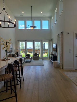 Model Home A spacious living room with high ceilings, tall windows, and a sleek open-plan design, offering abundant natural light.