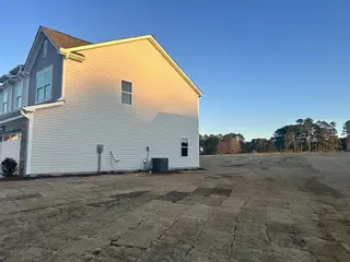 A modern home with siding and large windows, surrounded by open landscape in Green Hill by Starlight Homes (Louisburg, NC).