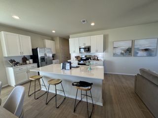 A modern kitchen with sleek white cabinets, a spacious island, stainless appliances, and light wood flooring.