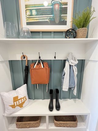 A chic mudroom with wall hooks, a framed car print, and stylish storage baskets.