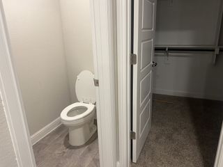A practical space featuring a separate toilet area and a carpeted closet, perfect for privacy and organization.