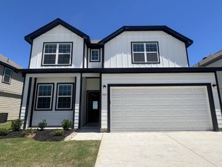 A modern white home with black trim and a two-car garage in Sycamore Landing by Legend Homes (Fort Worth, TX).