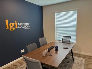 A modern office space featuring a sleek wooden desk, neutral chairs, and a bold navy accent wall with company branding.