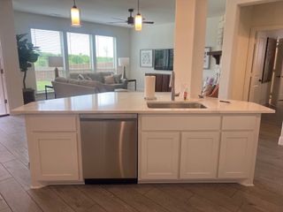 Model Home A modern kitchen with a sleek island, stainless steel appliances, and a view into a cozy living area with ample natural light.