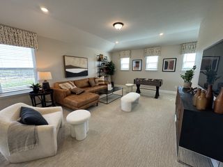 A cozy living room with a leather sectional, foosball table, modern art, and natural light filtering through patterned valances.