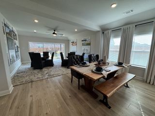 Model Home Spacious dining area with a wooden table, elegant chairs, large windows, and light wood flooring for a modern ambiance.