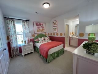 A cheerful bedroom with floral patterns, playful wall decor, and a connected bathroom in Solterra Texas by Highland Homes (Mesquite, TX).