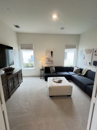 A cozy living room featuring a sleek dark sectional sofa, neutral carpet, and modern decor for a relaxing ambiance.