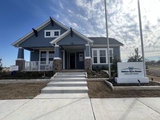 A charming blue home with a cozy porch and landscaped yard in Midtowne by William Ryan Homes (Midlothian, TX).