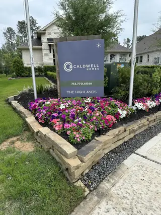 Charming display of vibrant flowers and signage at The Highlands by Caldwell Homes in Porter, TX, enhancing the curb appeal.
