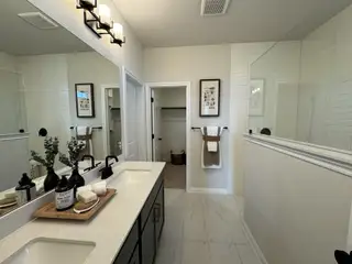 A modern bathroom with dual sinks, sleek black fixtures, white tiles, and elegant lighting.