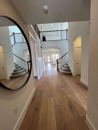 Model Home A spacious entryway with wooden floors, accented by a large circular mirror and stylish staircase.