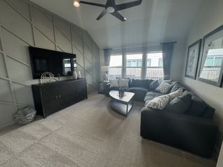 A cozy living room featuring a sectional sofa, geometric accent wall, and large windows for plenty of natural light.