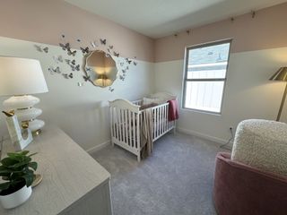 Model Home A baby’s nursery with a soft and elegant theme, featuring a white crib against a dual-tone wall with soft pink and white.