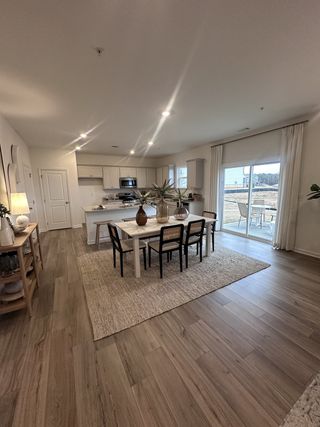 A spacious open-plan kitchen and dining area with wood floors, neutral tones, and abundant natural light.