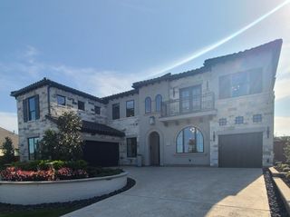 Elegant stone-and-stucco home with lush landscaping in Star Trail 76' by Britton Homes (Prosper, TX).