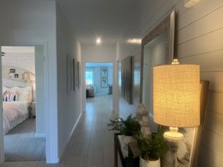 A welcoming hallway with stylish décor, featuring a well-lit lamp, wall art, and a glimpse into a cozy bedroom.