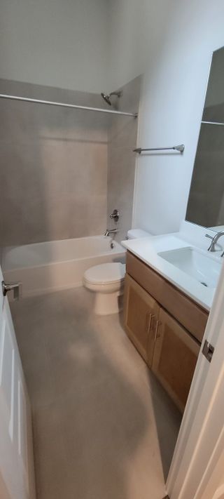 Model Home A cozy bathroom featuring a bathtub, wooden vanity with a sink, and neutral tile accents.
