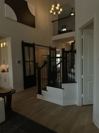 A modern interior featuring elegant lighting, sleek black railings, and an open layout with wooden flooring.