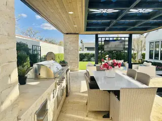 Model Home Elegant outdoor patio with a built-in grill, wicker dining set, and plush seating area, ideal for entertaining.