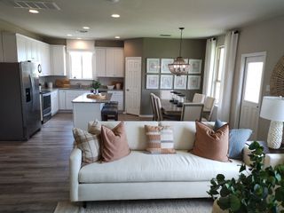 Open-concept kitchen and dining area with white cabinetry, granite countertops, and a contemporary chandelier.
