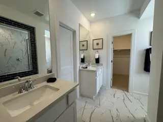 A modern bathroom featuring marble-pattern tiles, sleek vanity, and a walk-in closet for a luxurious feel.