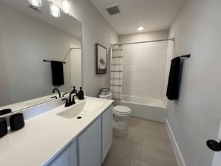 Model Home A sleek bathroom featuring a white vanity, black fixtures, and a subway-tiled bathtub for a modern, clean look.