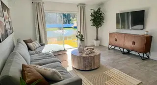 Model Home A stylish living space with a sectional sofa, large TV, and serene water views in Kings Crossing by Meritage Homes (Jacksonville, FL).