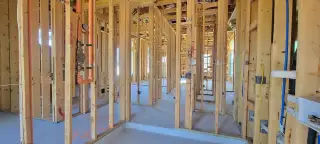 A framed interior showcasing the early stages of construction with exposed wooden beams and visible piping.