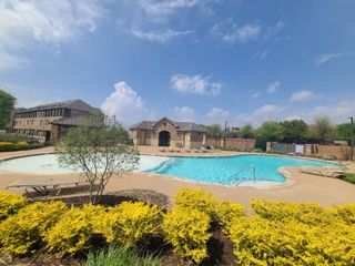 A luxurious pool and clubhouse area with landscaped grounds in Wade Settlement by Megatel Homes (Frisco, TX).