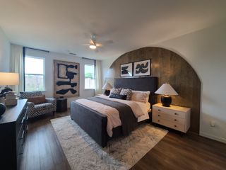 Elegant bedroom with wood accents, abstract art, a cozy armchair, and plush bedding for a stylish, inviting space.
