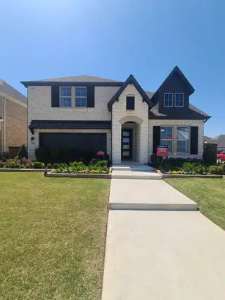 Street view A beautiful two-story brick home with manicured landscaping in Valencia on the Lake by Beazer Homes (Little Elm, TX).